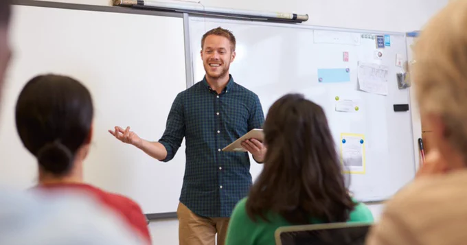 Male teacher standing in front of a classroom
