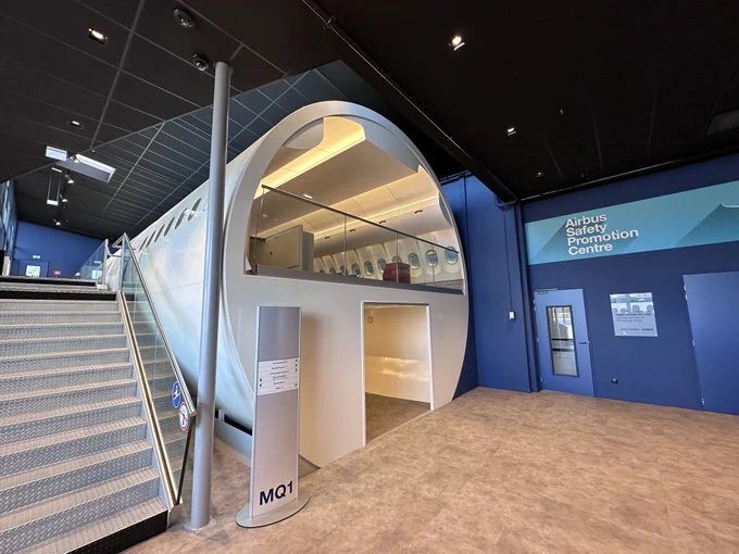 Airbus Safety Promotion Center. A mock-up of the cross section of an aircraft serves as the start of the center, sitting alongside a set of stairs.