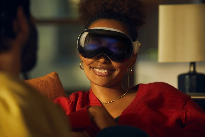 Someone looking like an idiot wearing a VR headset with a big grin while sharing a couch conversation with another person