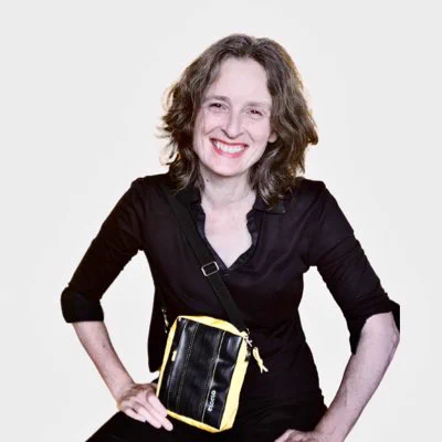 Picture of me wearing a small flight bag. The side panels are yellow, made from life raft ; the front and back are black, made from bicycle inner tubes. Lining and zip pull are from a tent.