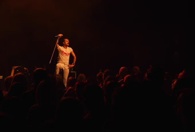 Singer in Flash stands stoic over a crowd of people