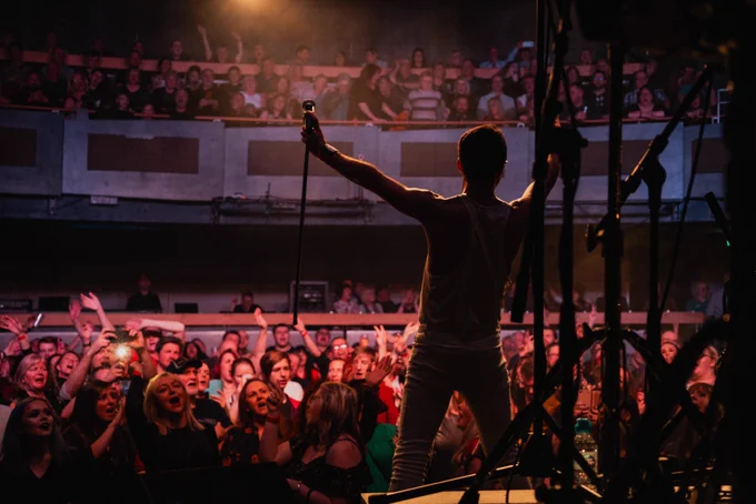 Singer of Flash on stage arms in the air over a hyped up crowd