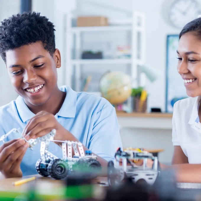 Two students working on project while smiling. 