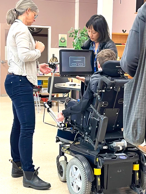 Pearl and Andrea adjust the mounting solution on a student's wheelchair.