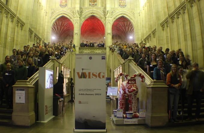 Photo of attendees at VMSG 2024. Everyone is stood up two sets of stairs in the entrance of a grand gothic building.