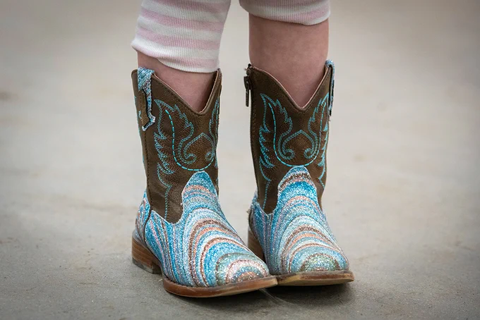 Brown and turquoise cowboy boots on a person's feet.