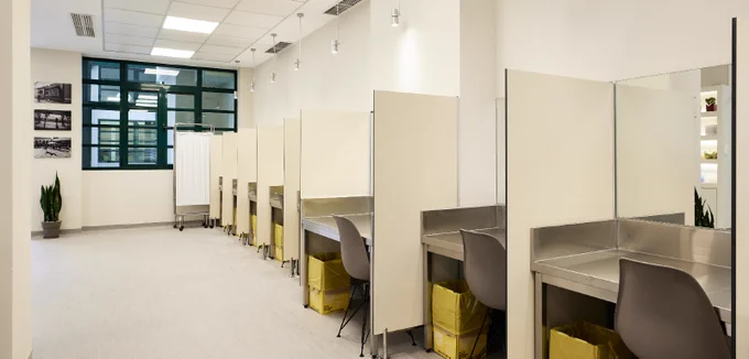 Image shows the interior of a Drug Consumption Room in Athens, Greece. There is a row of eight booths with a window in the background.