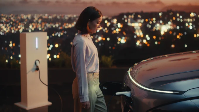 2 still images from the campaign, showing the woman and the car on the foreground and the city lights on the background.