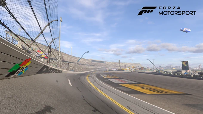 This screenshot shows the Daytona International Speedway on a bright and sunny day, with a clear blue sky and scattered clouds. The stadium with the grandstands is located on the left side of the image and is filled with enthusiastic fans eagerly watching the track. On the right side of the picture you can see the inside of the oval, which is filled with tents from various sponsors, campers and other amenities. In the upper right corner of the image, next to the Forza Motorsport logo, you can see a blimp hovering over the track.