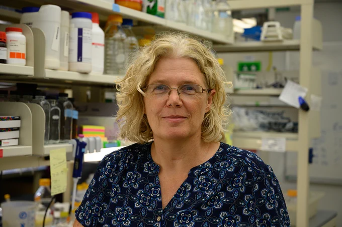 Veronica Hinman smiles at the camera with her lab as the background.