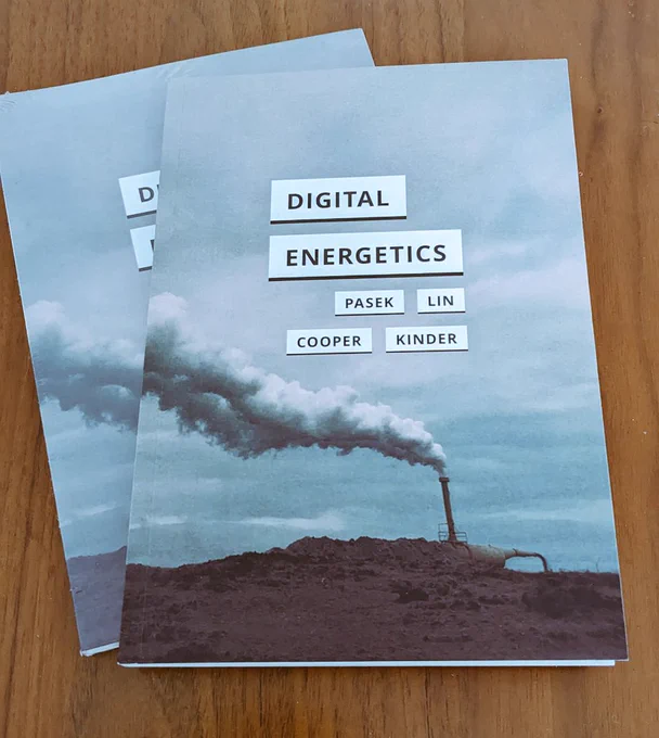 Two copies of the book Digital Energetics. It's a small square-ish paperback with a cover image of a pipe letting out a huge plume of steam in a steaming desolate landscape (it's Greenland).