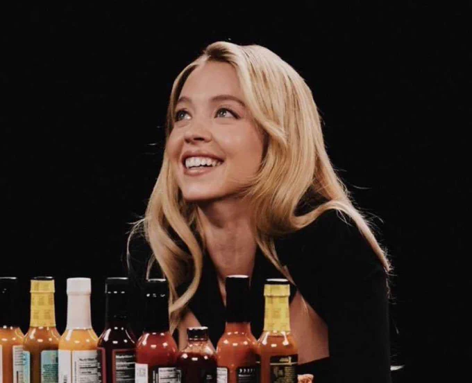 Image of Sydney Sweeney on Hot Ones looking up and smiling.