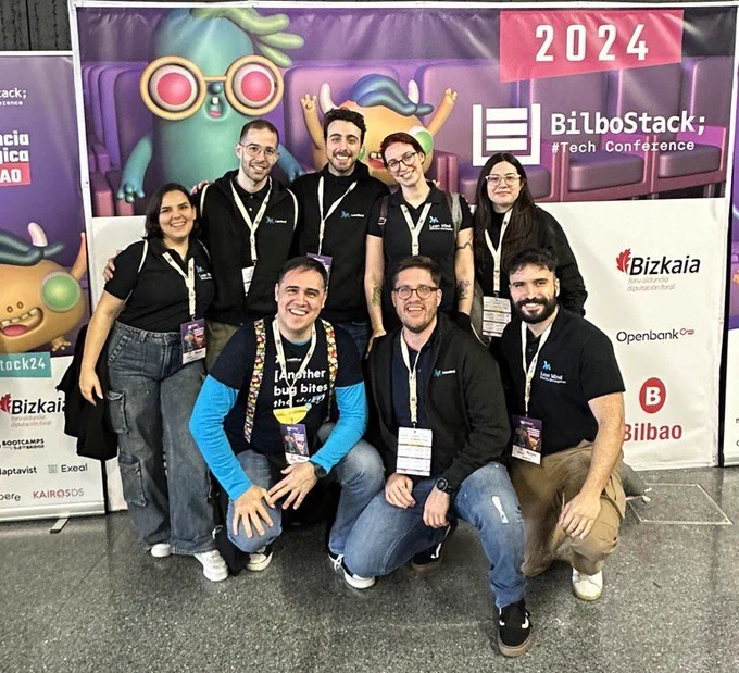 Team Lean Mind de izquierda a derecha arriba: Ana, Adrián, Airán, María, Ari. De izquierda a derecha abajo: Mánu (yo), Cristian, Miguel. Detrás nuestra el cartel de la Bilbostack 2024. Todos con las camisetas y sudaderas negras de Lean Mind con su imagotipo, logos y frase: Efficient People. Sonrisas radiantes en todas las caras