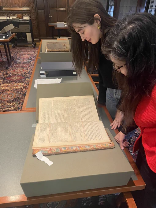 Two people marveling at a beautiful big book, centuries old but in somewhat miraculously superb condition