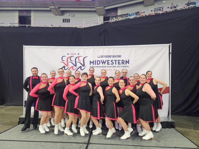 Group of adult skaters posing in front of a banner 