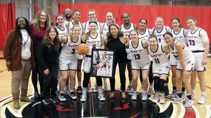 The women's basketball team gathered around Christina Antonakakis in celebration of her breaking the MIT program record for career points
