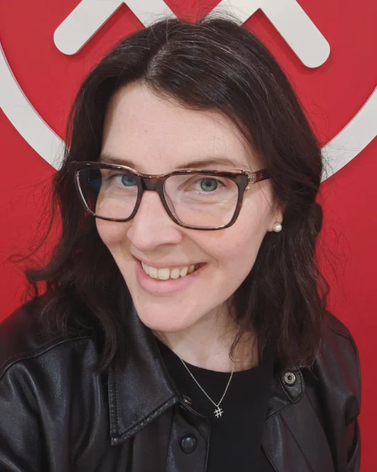 Selfie of me in front of CLC logo and red wall