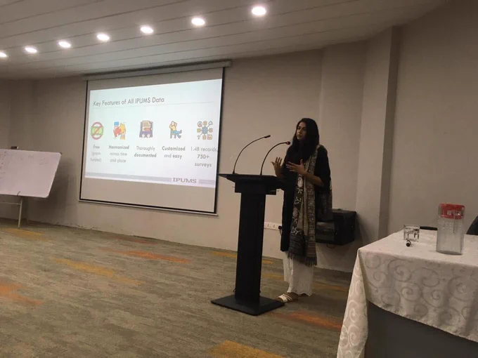 Mehr Munir standing behind a mic at a podium giving the talk