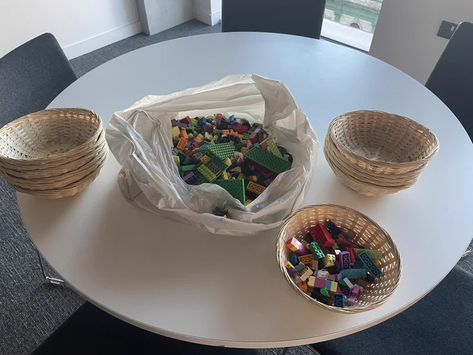 A plastic bad of Lego and baskets for people to take Lego