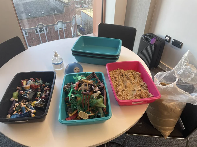 Trays, sand and figures to make scenes such as cars, animals and people
