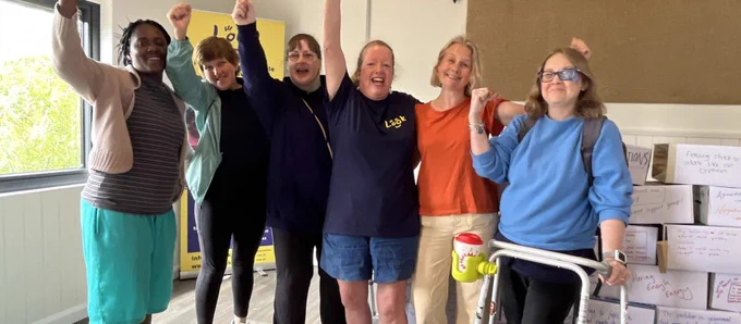 Triumphant photo of group of parents in front of a LOOK banner with their arms raised in the air and big smiles on their faces. Jane Ring, LOOK's PSG Lead is in the centre wearing a LOOK Tshirt. 