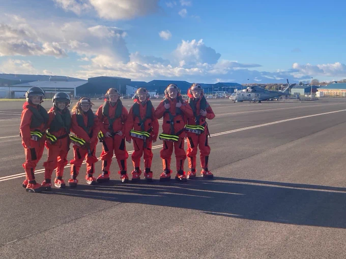 Seven Unit staff on a runway with Royal Navy Merlin Mk2 helicopter in the background