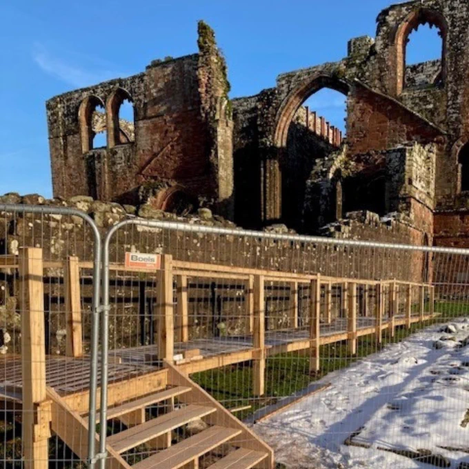 A wooden walkway leading to the abbey ruins