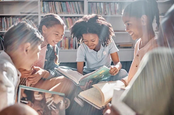 Image of four children reading bookings in school library setting