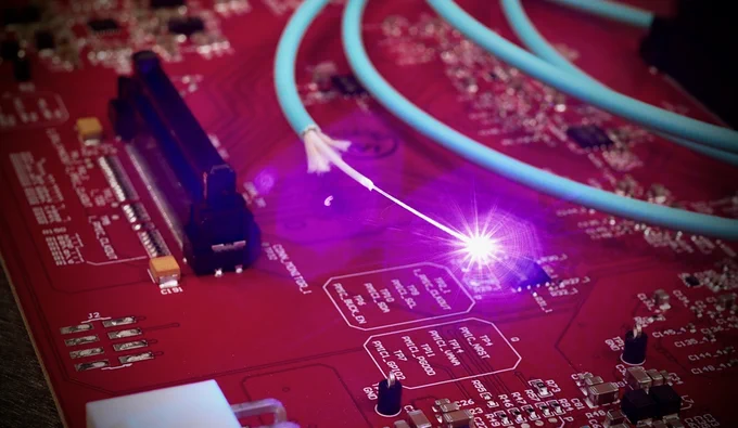 Light traveling through an optical fibre sitting on top of a conventional electronic circuit board.