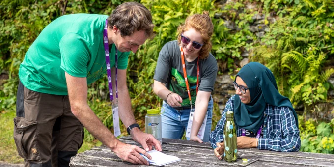 Ecologists looking at a notebook on an outdoor table.