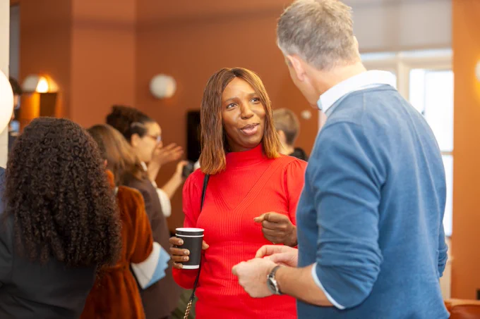 First image of a crowd of business people networking. One woman is in a red dress, talking to a man in a blue jumper. The second image is a satellite map of Clifford Road E17 and the streets around it.