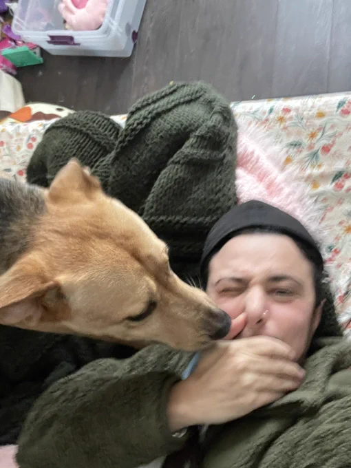 Blurry picture of me laying down and my dog licking my face