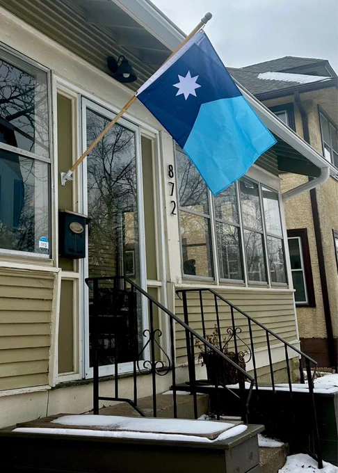 New Minnesota state flag hanging from a porch of a craftsman house