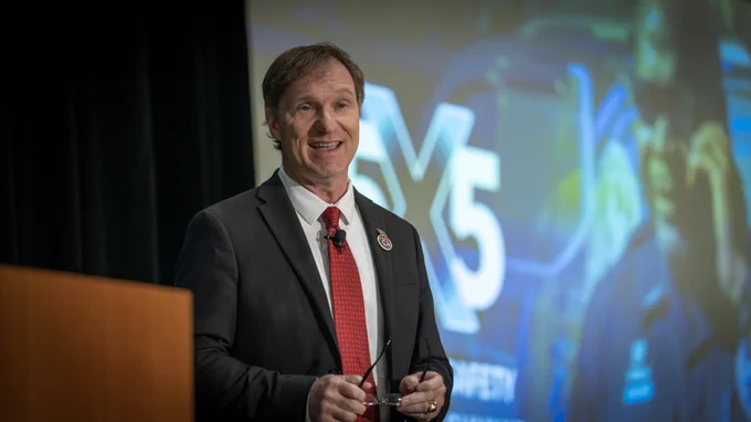 FirstNet Authority Executive Director/CEO Joe Wassel speaking in front of a 5x5 panel screen