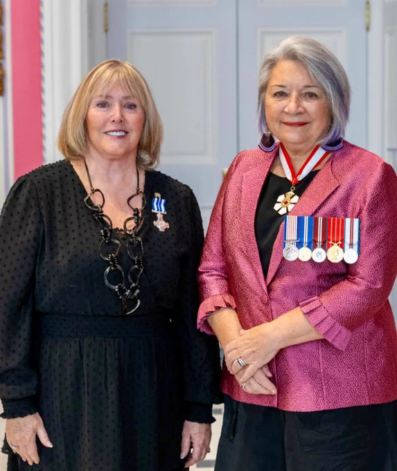 Kathryn Blain, Wearing her newly awarded Meritorious Service Cross, And standing to the left of a woman wearing several medals