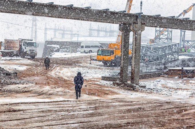 a construction site with workers in the snow