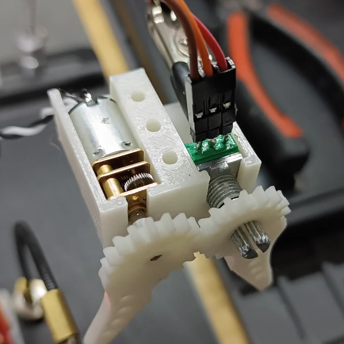 Closeup of the claw mechanism. The body and both parts of the claw are 3D printed. The left side is driven by a DC motor with a reduction box, while the right side follows the right side movement (thanks to the geared claw rotation axis), turning a potentiometer as the claw opens or closes, providing positional feedback to the control board.