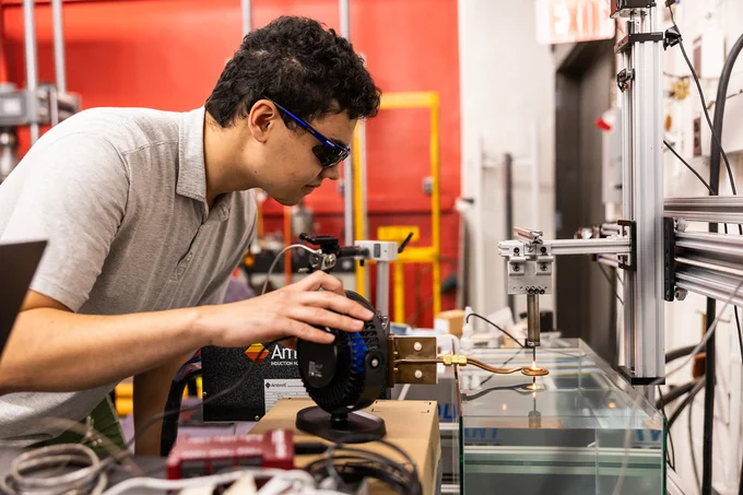 A student in Zack Cordero's lab uses a 3D printer to print metals.