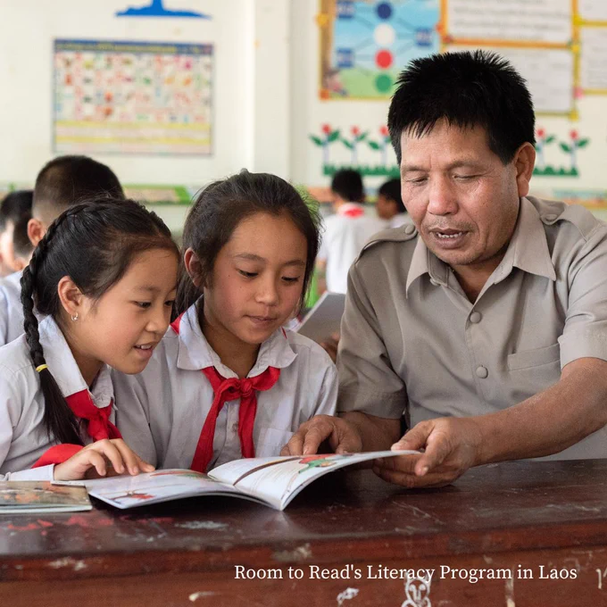 A primary school teacher reads with two students in a classroom reading corner in Laos. 