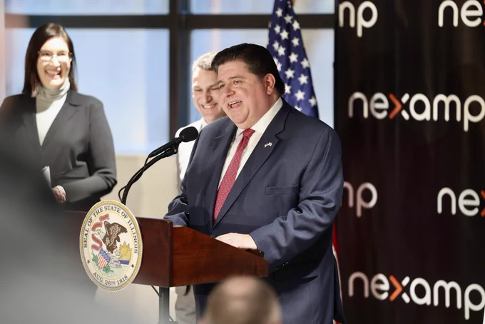 Governor Pritzker speaks at a podium in front of a Nexamp backdrop.