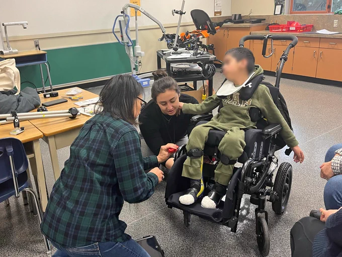 SET-BC OT, Pearl attaches mount with Tessa to student's wheelchair.