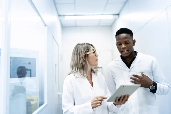 two doctors in white coats having a discussion in a hallway. 