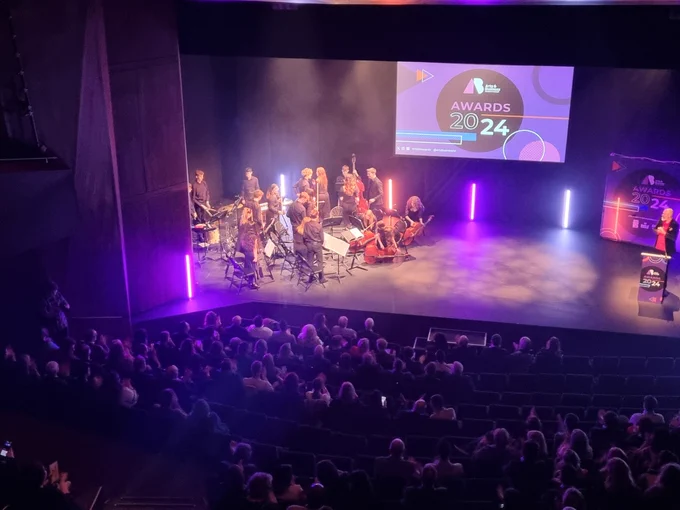 Ulster youth orchestra performing the opening piece on stage at the lyric theatre. Crowds applauding. 
