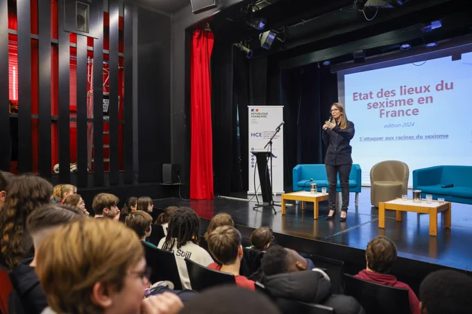 Aurore Bergé, ministre déléguée chargée de l’Égalité entre les femmes et les hommes et de la Lutte contre les discriminations, s'exprimant debout sur scène. Vue sur les 3 premiers rangs.