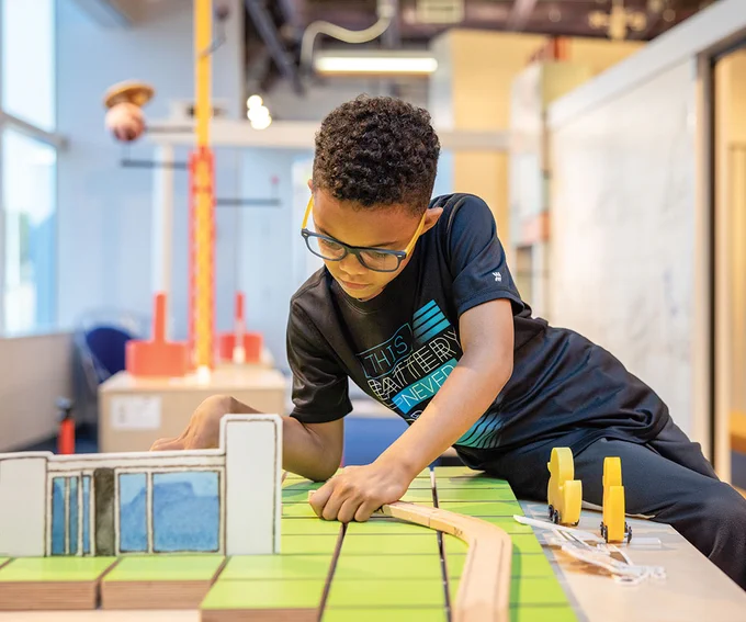 An image of a boy playing at a city building station in the Questioneers event.