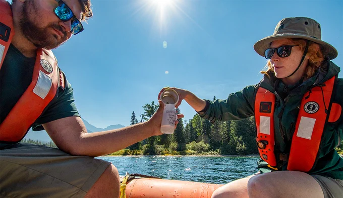 Two Parks Canada staff collect water samples from a boat