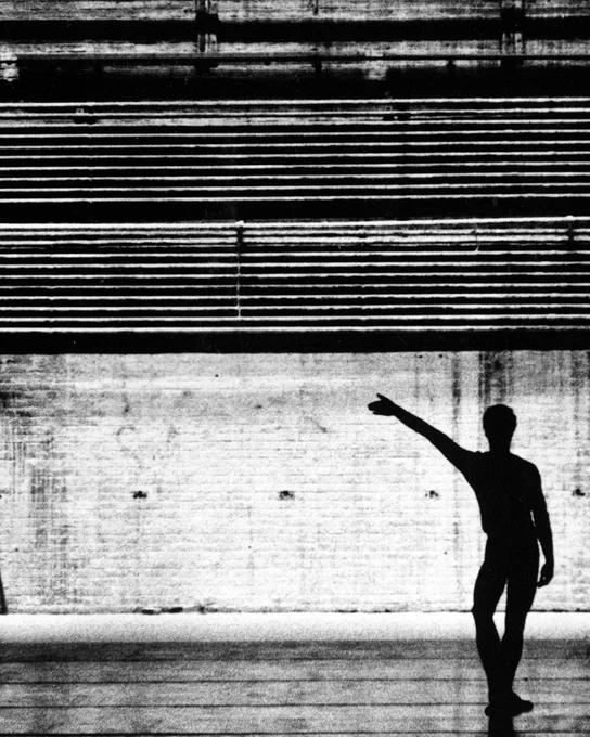 Merce Cunningham posing with his right knee bent and his right arm outstretched at a 45 degree angle.