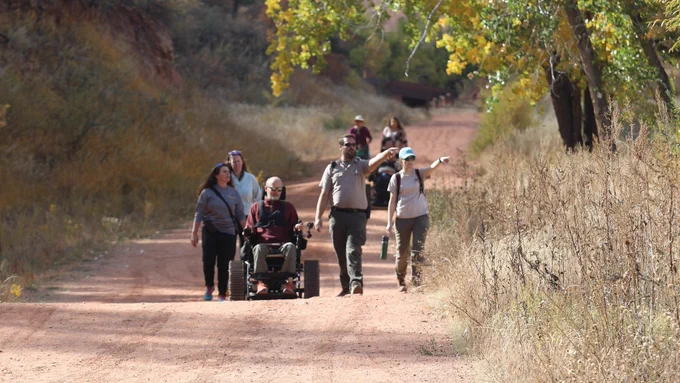 Group of residents including one who is using a Trackchair to travel on a trail