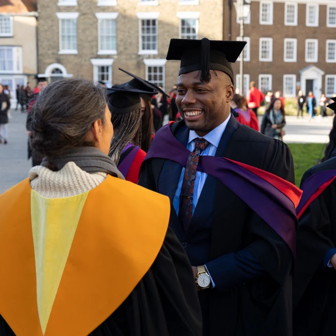Photo of a graduate smiling while talking to an academic