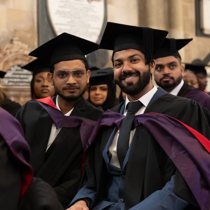 Photo of two graduates smiling to the camera